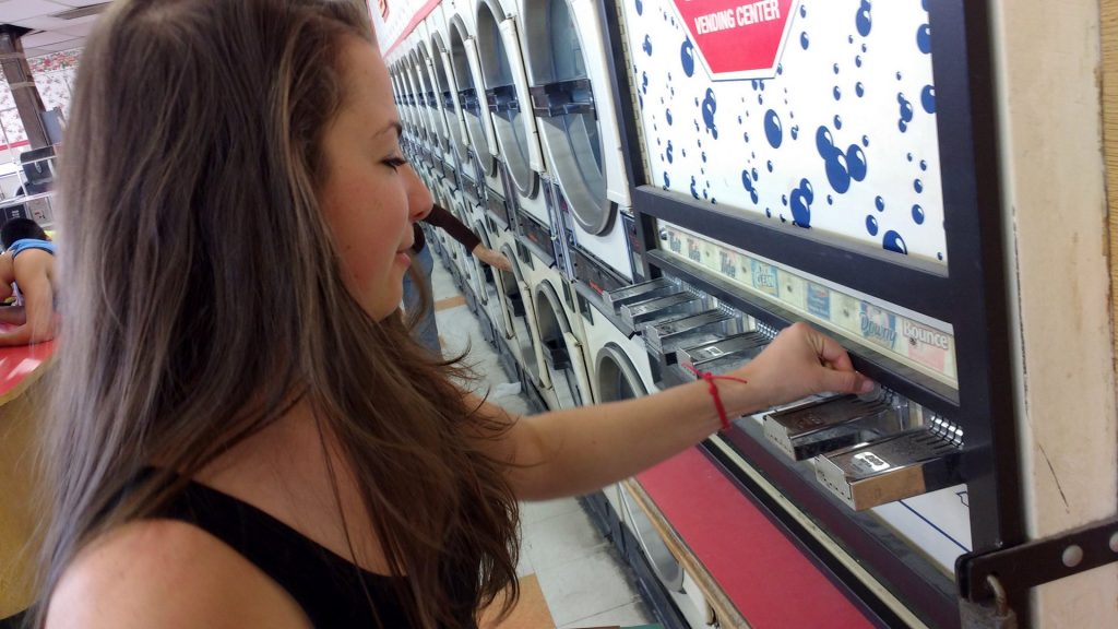 Terézia Ligačová puts quarters in a vending machine that dispenses small packets of soap