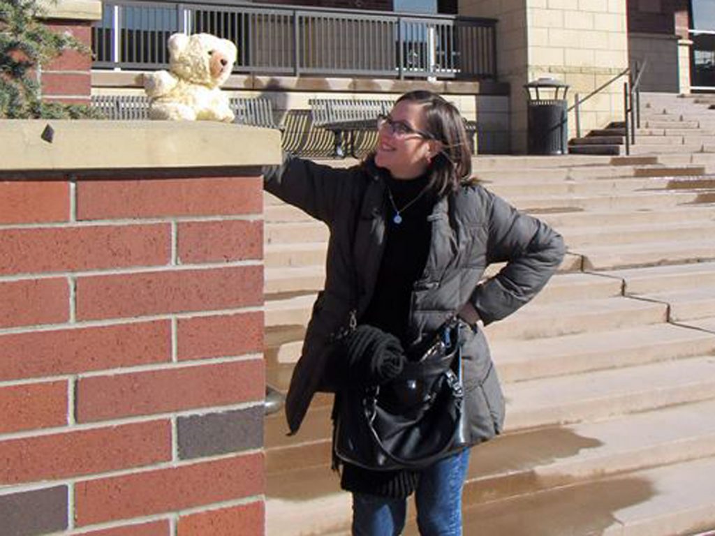 Ludmila and Ambyr Noelle (a plush bear) outside a campus building