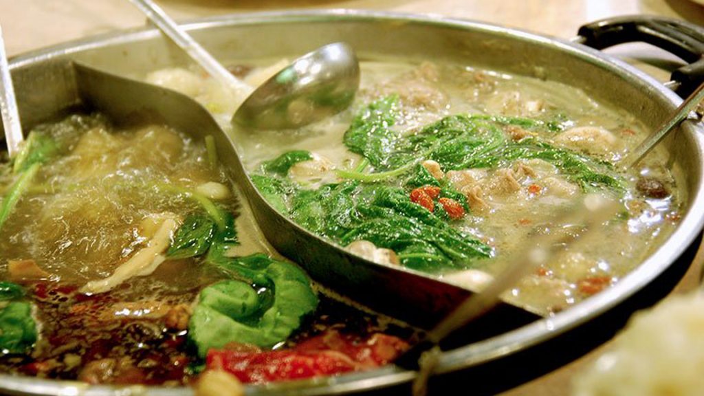 photo of a large hot pot divided into the shape of a yin-yang symbol