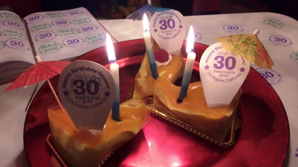 3 slices of dessert on a big red plate with 3 candles and "Happy Birthday Gizem" signs