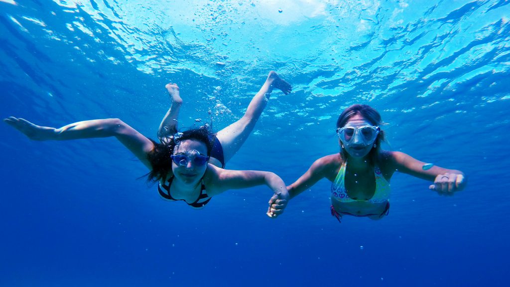 two people snorkeling and holding hands underwater