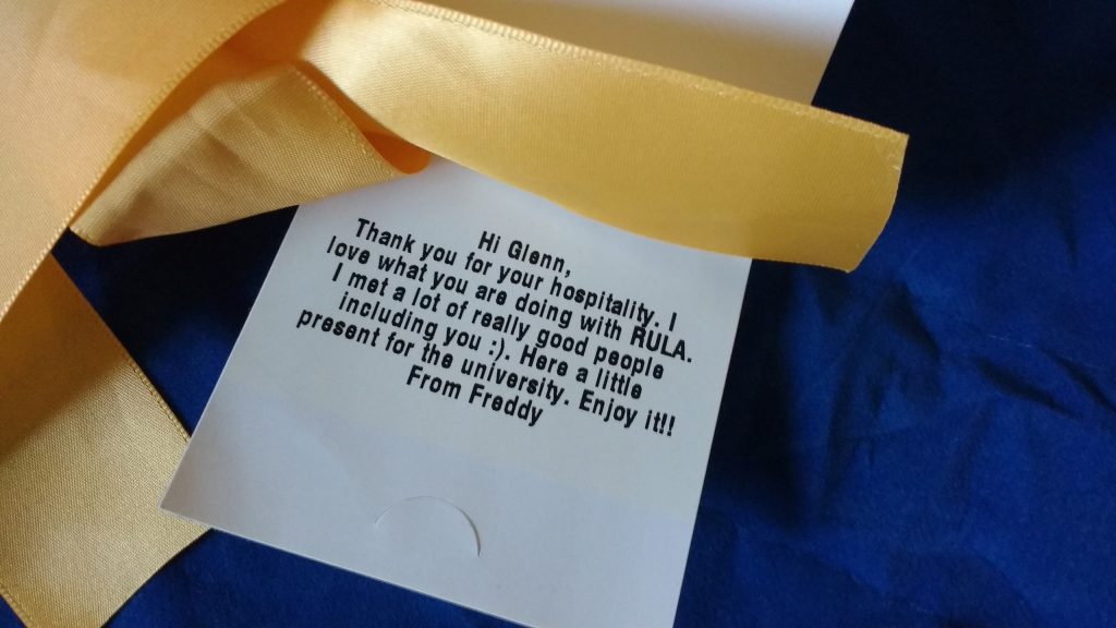 gift tag on Freddy's Air Mattress bag with the text "Hi Glenn, Thank you for your hospitality. I love what you are doing with RULA. I met a lot of really good people, including you. Here is a little present for the university. Enjoy it! From Freddy."