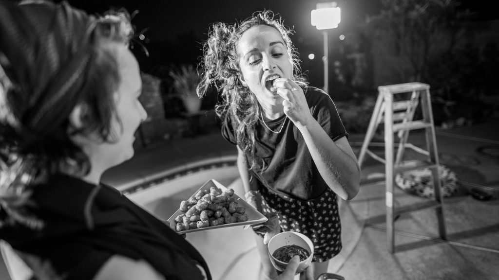 Meri tastes a tater tot from a tray offered by Ophelie