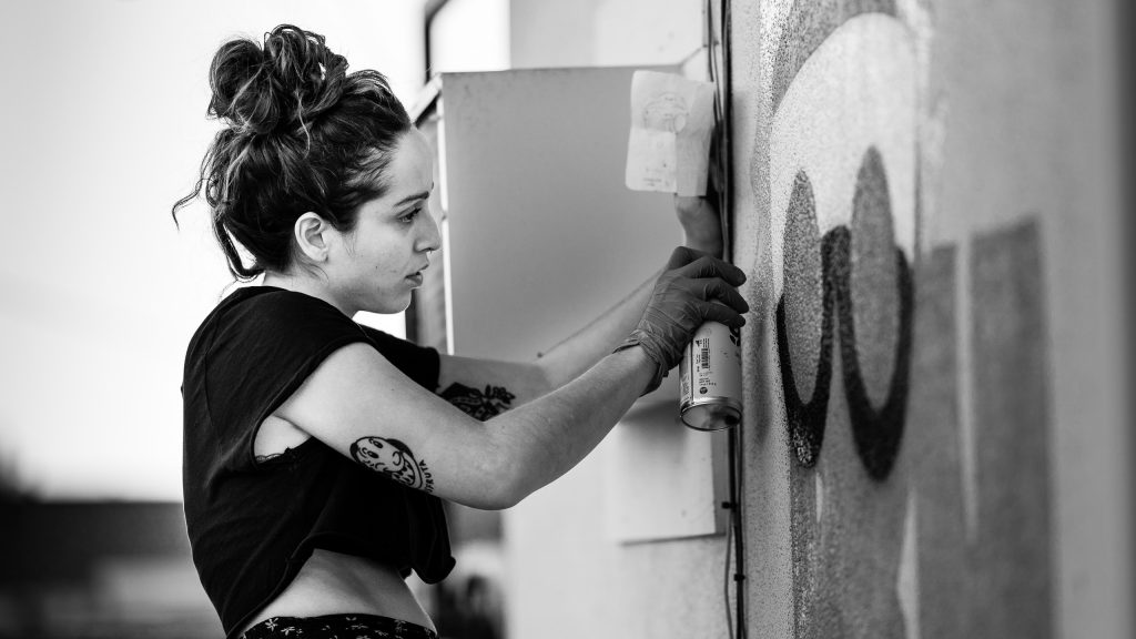 Merijein Saperas painting a graffiti writing mural of the letters "RULA" at Runaway University in Los Angeles, California.