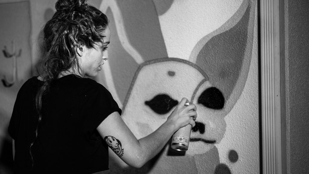 Merijein Saperas painting a graffiti writing mural of the letters "RULA" at Runaway University in Los Angeles, California.