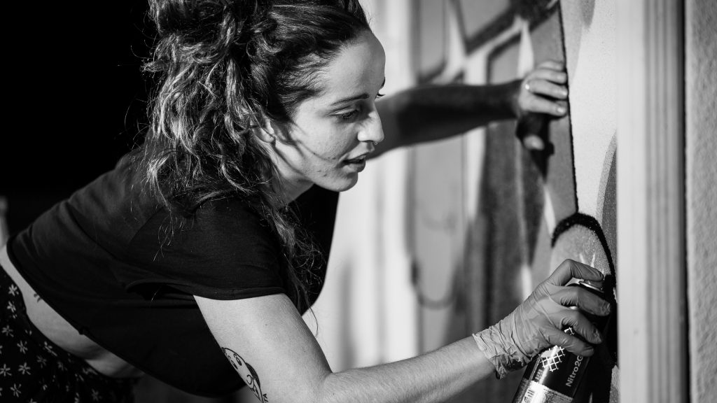 Merijein Saperas painting a graffiti writing mural of the letters "RULA" at Runaway University in Los Angeles, California.