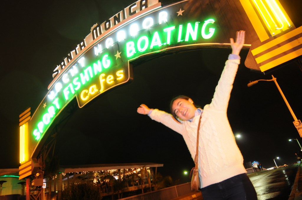 Margaret (Yin Yung) Chung spreads her arms under the neon sign at the entrance to the Santa Monica Pier