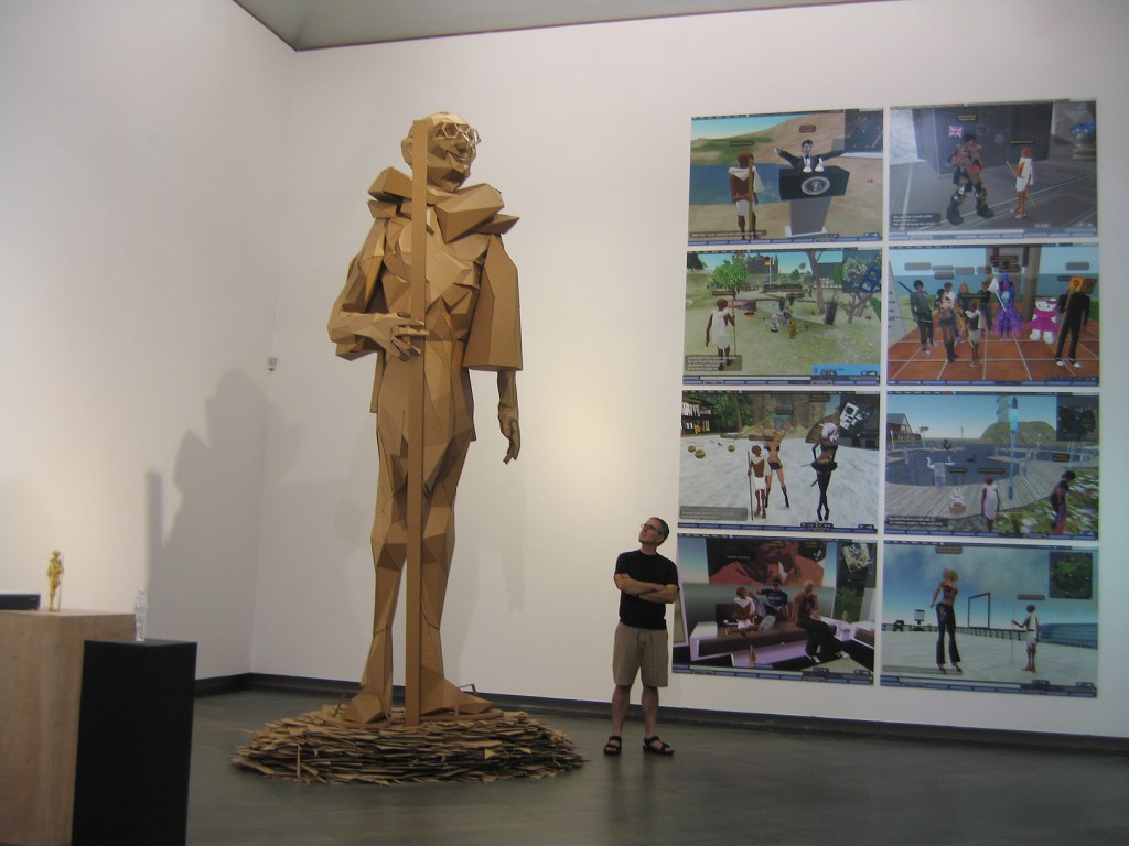 Joseph DeLappe standing next to a large sculpture of his Gandhi avatar