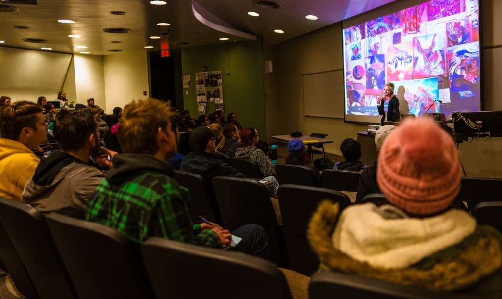Art 110, Introduction to the Visual Arts students listening as airbrush artist and Street Muralist Lizzie Green shows slides of her work