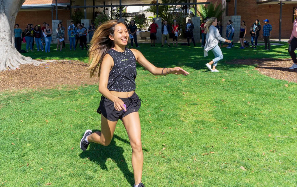 a student running with a foam letter representing a work of art