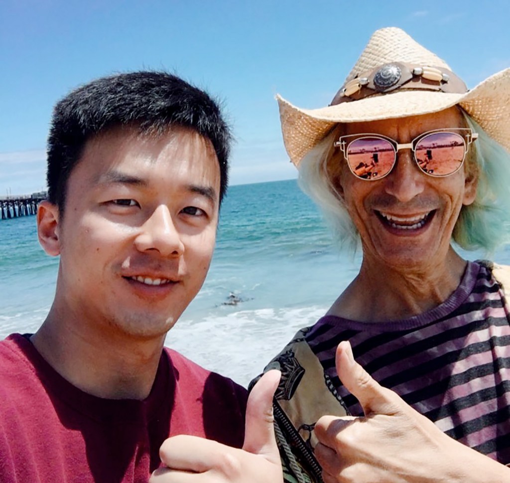 Kewei & Glenn on the beach near the Seal Beach Pier with bright ocean water behind them