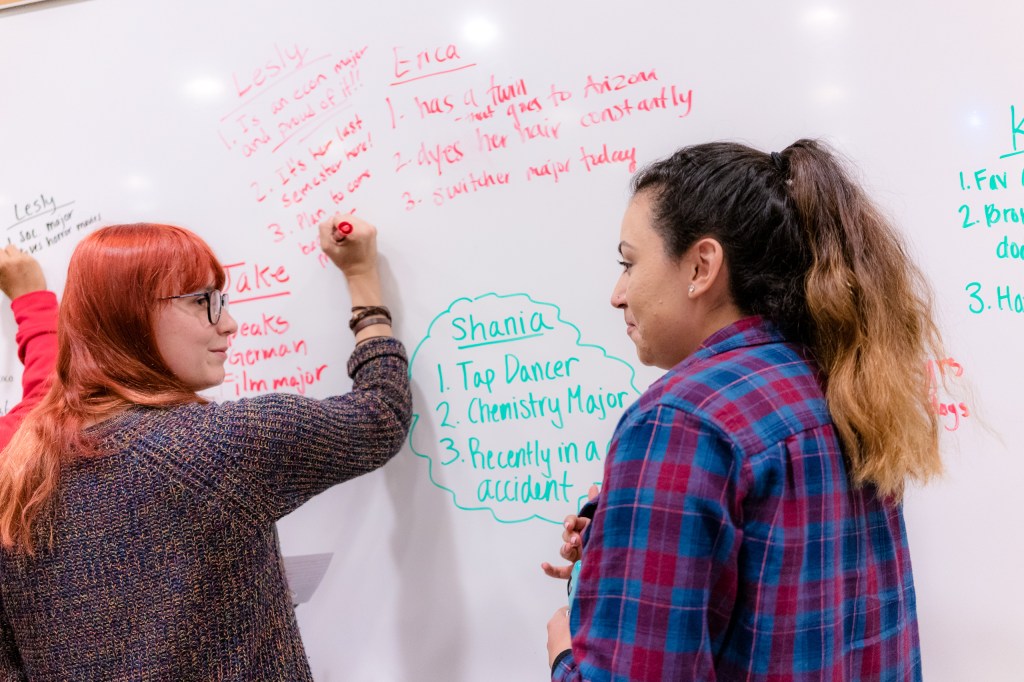 Erica Lander & Lesly Carrillo writing on the white board in room Psychology-150 at Long Beach State University
