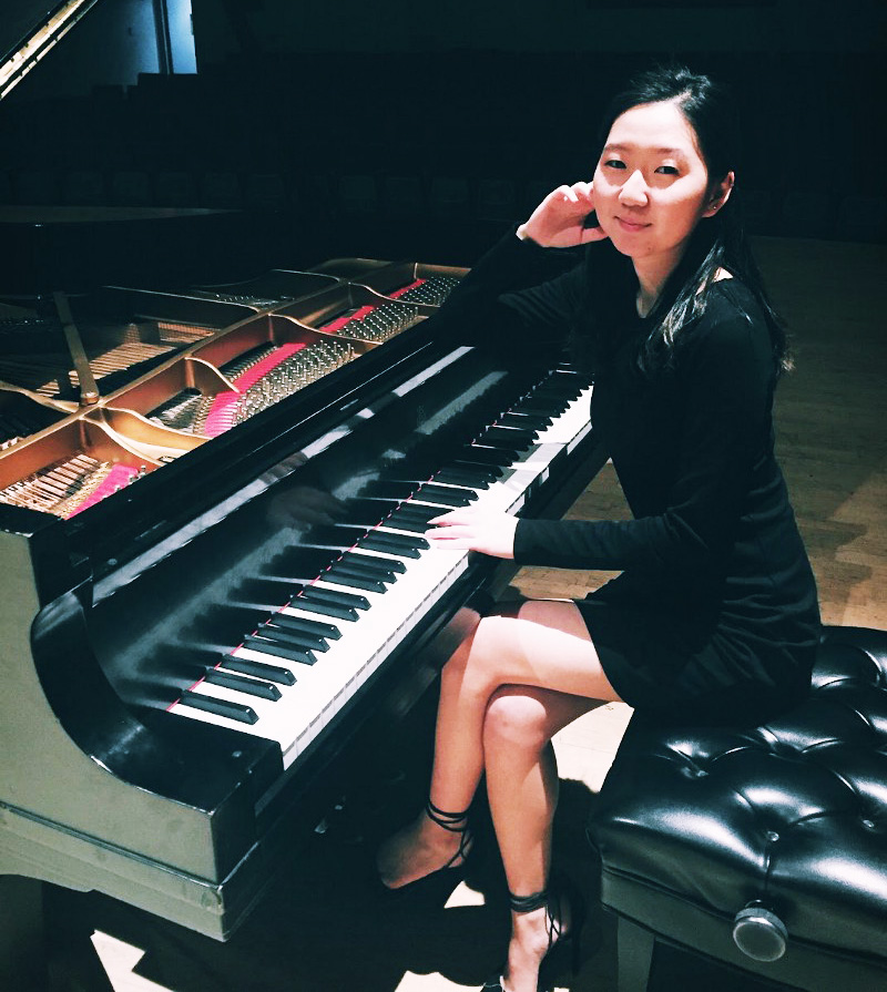 Yeunje Kim in a black dress and seated at a grand piano
