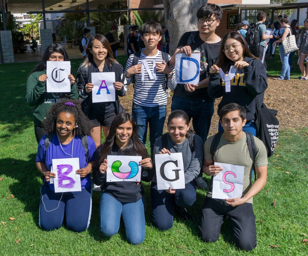 a group of students, each holding an individual letter that together spell out "Candy Bugs"