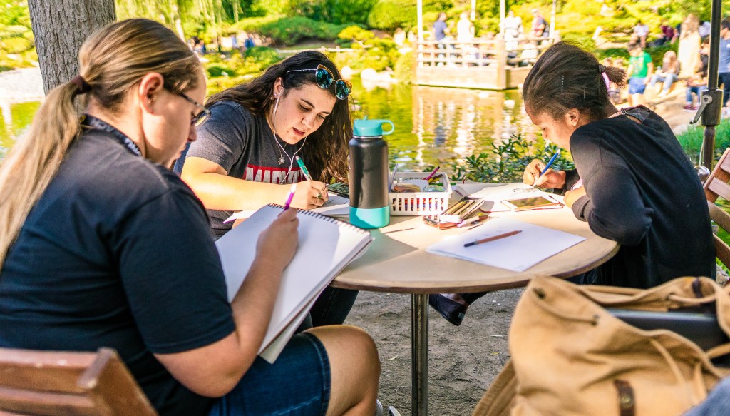 students sitting at at table in the Japanese Garden and drawing some of the garden elements