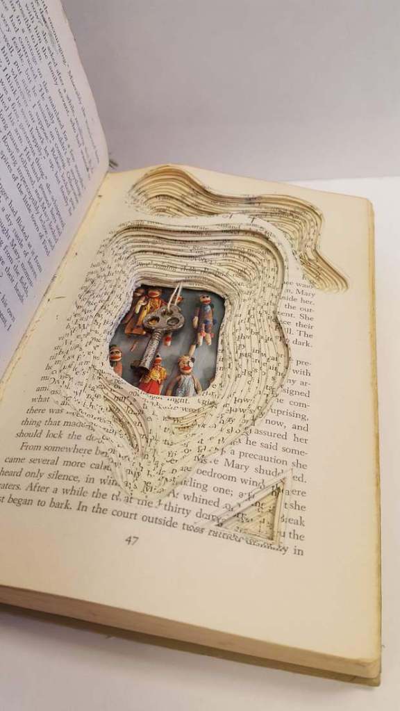 Image of an artist's book showing cut pages and inserted objects