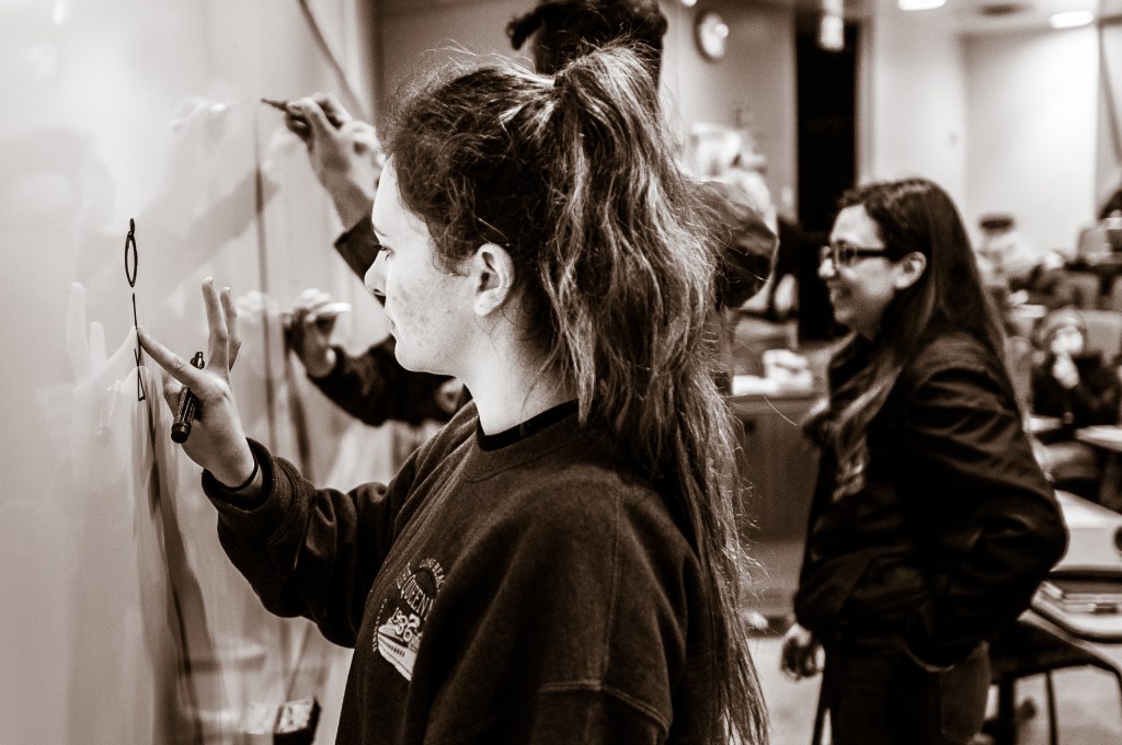 Choreographer and dancer Kaelie Osorio drawing at a white board in classroom Psy-150 on the campus of Long Beach State University.