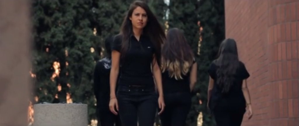frame from New Beginnings featuring a young woman walking across a university campus