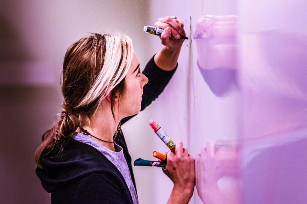 Artist Lizzie Green drawing on a whiteboard at Long Beach State University